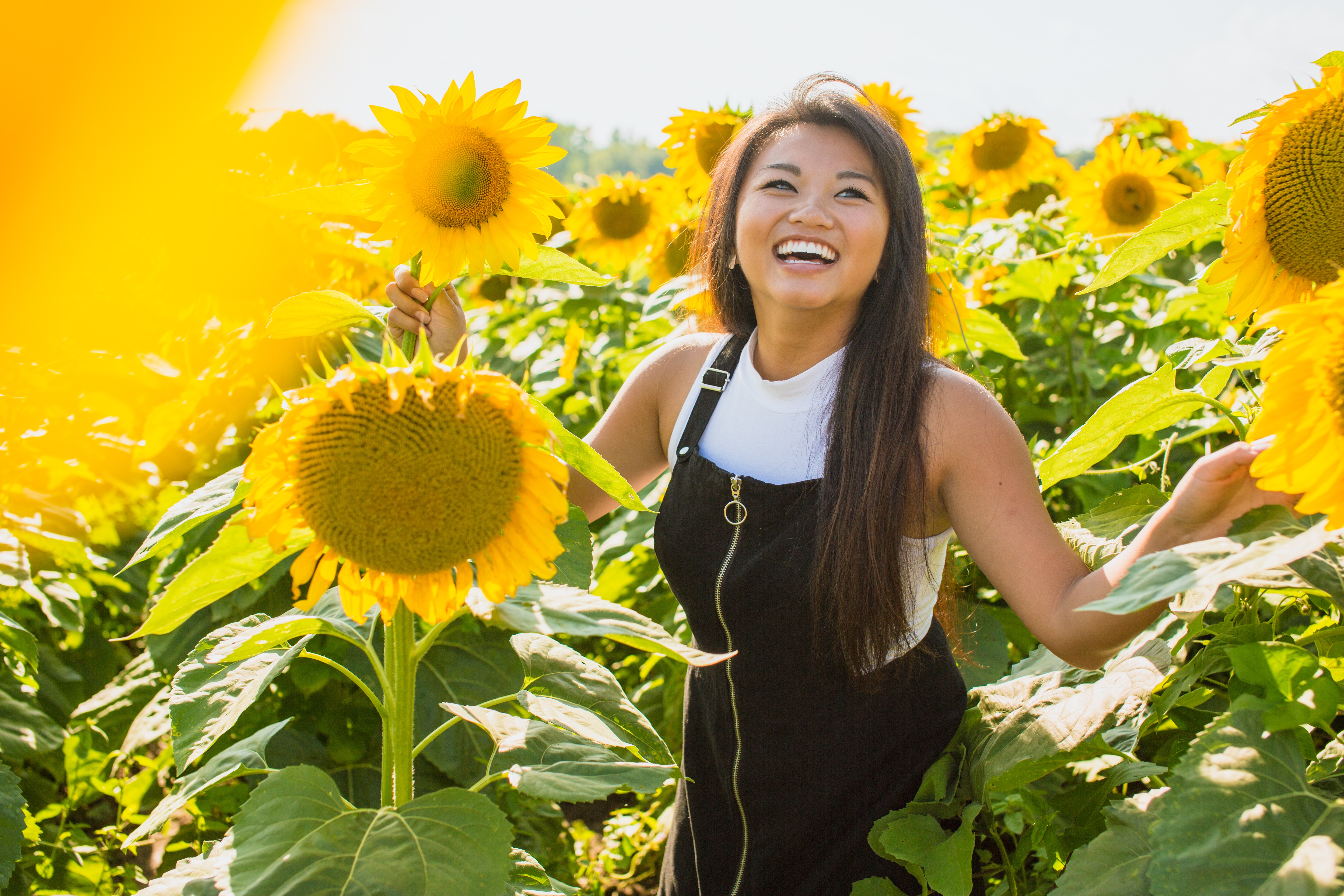 teen patient with invisalign smiling in a sunflower farm