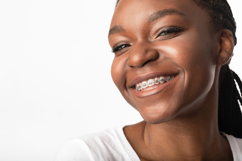 woman smiling with braces after cleaning teeth with Waterpik 